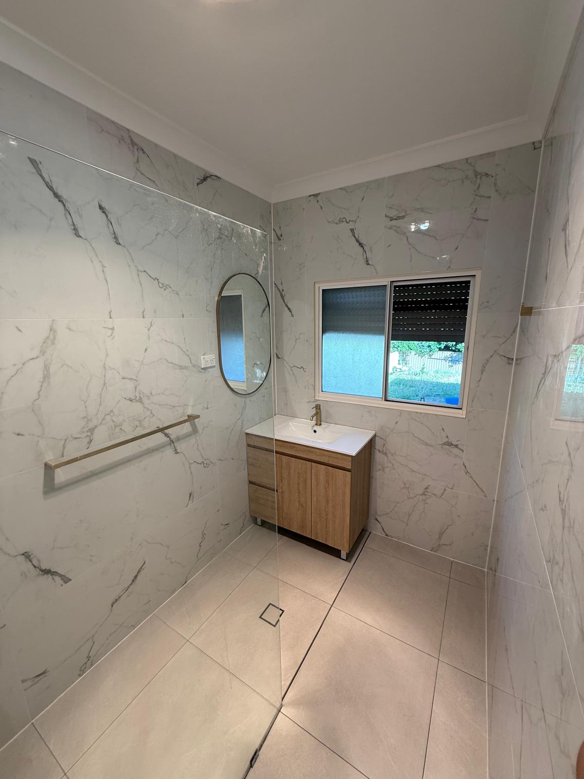 Vanity tiling — marble walls with gold fixtures and oval mirror
